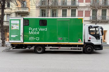 Punt verd mobil. Barcelona caddesinde park etmiş yeşil belediye mobil geri dönüşüm kamyonunun yan görüntüsü, çevresel atık toplama ve şehir temizleme hizmetlerini destekliyor