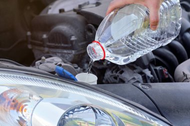 Arabadaki yıkama tankına damıtılmış su (çamaşır suyuna alternatif) döken adam, elinde temiz plastik şişe tutan detaylar