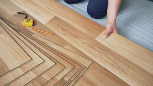 Man installing laminated floor tiles over white foam base layer, detail on his hands positioning boards — Stock Footage Man Installing Laminated Floor Tiles White Foam Base Layer Detail Video Clip
