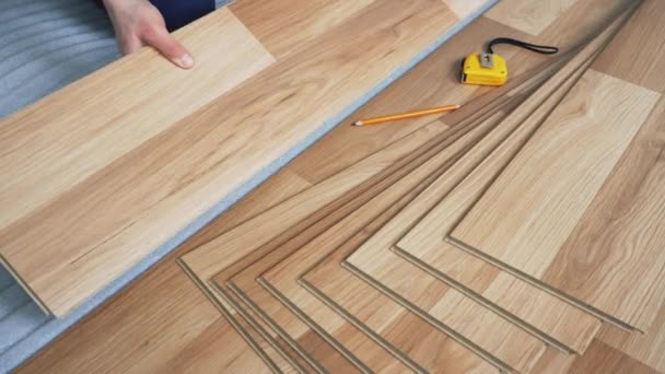 Man installing laminated flooring, fitting wooden tiles, pencil and tape measure near — Stock Footage Man Installing Laminated Flooring Fitting Wooden Tiles Pencil Tape Measure Video Clip