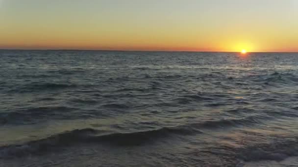 橙色的太阳落在海面上 平静的海浪在前景中 — 图库视频影像