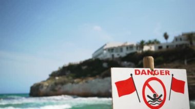 Tehlike, kırmızı bayraklı yüzme işareti yok, arka planda bulanık rüzgar dalgaları var.