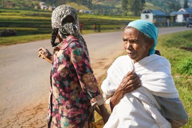 Manandoana, Madagaskar - 26 Nisan 2019: Güneşli bir günde çalıştıkları pirinç tarlasının yanında duran iki yaşlı Malagasy 'li kadın. Afrika 'nın bu bölgesindeki insanlar fakir ama neşelidir..