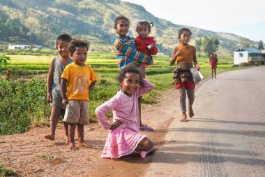 Manandoana, Madagaskar - 26 Nisan 2019: Yolda pirinç tarlasının yanında oynayan bir grup meçhul çocuk, arka planda küçük tepeler, Madagaskar halkı fakir ama neşeli, özellikle de çocuklar
