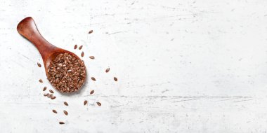Keten tohumu ile küçük ahşap kepçe - Linum usitatissimum, masa gibi beyaz taş üzerinde, yukarıdan görünüm, metin için sağ taraf için boşluk