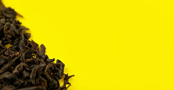 Loose black tea Assam variety on yellow board, view from above space for text right side — Stock Photo, Image