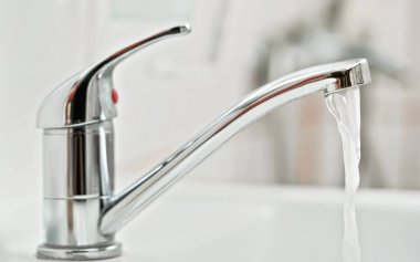 Musluk musluğu, akan su, bulanık banyo arka planı, yandan görüş