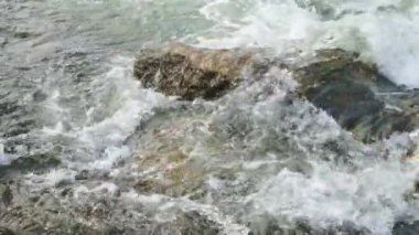 Güneşli bir günde kayaların üzerinden akan taze bahar nehri, yavaş çekim videosu