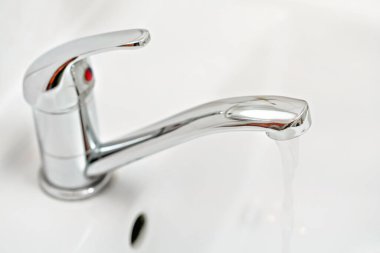 Su akan krom musluk, bulanık banyo arka planı.