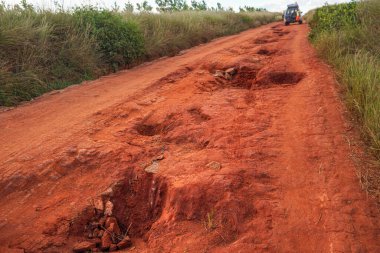Kırmızı toz ve çamur yolu yağmurdan sonra oluşan büyük delikler ve tümseklerle kötü durumda. Madagaskar, Sendrisoa yakınlarındaki yağış mevsiminde Andringitra Ulusal Parkı rotaları son derece kötüdür.