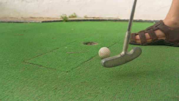 ミニゴルフをする男 行方不明簡単に近い穴 鋼クラブの頭と白いボールの詳細 — ストック動画