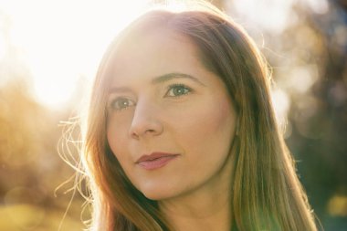 Uzun siyah saçlı, güzel bir bokeh ve güçlü bir arka plan ışığı olan genç kadın portresi.