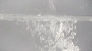 Su tanka döküldü, birçok hava kabarcığı yüzeye yükseldi, gri zemin