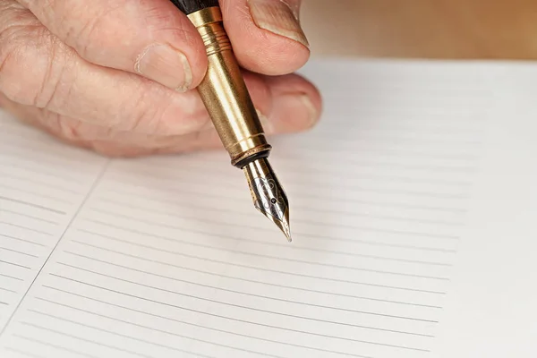 Penna stilografica color oro nella mano della donna anziana che sta per scrivere qualcosa sulla pagina vuota del pianificatore quotidiano, dettaglio primo piano — Foto Stock