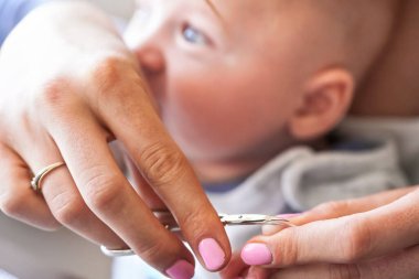 Erkek bebeğin tırnaklarının annesi tarafından kesilmesi, makas ve parmak uçlarındaki detaylar...