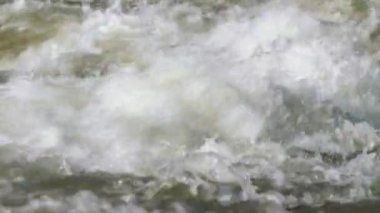 Yakından bakınca, güneşli bir günde nehirde akan su beyaz dalgalar oluşturuyor.