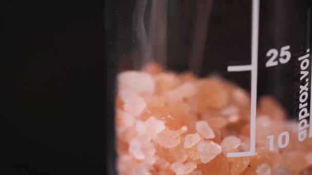 Orange Pink Crystals Dropped Glass Beaker Closeup Detail Black Background — Vídeo de stock