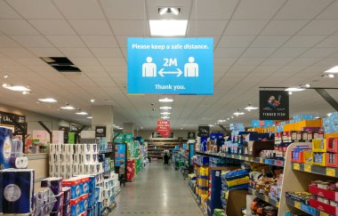 Londra, Birleşik Krallık - 21 Ağustos 2020: Süpermarket koridorunun üzerindeki mavi ve beyaz bilgi tablosu, müşterileri Coronavirus covid 19 salgını sırasında sosyal uzaklık çalışması yapmaya sevk etti