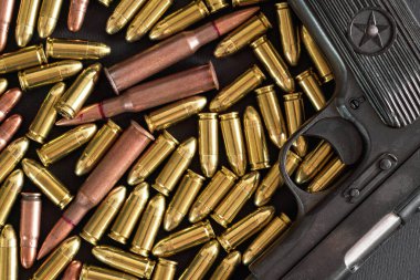 Sarı pirinç ve kahverengi bronz mermiler, yanında siyah silah, yukarıdan yakın plan.