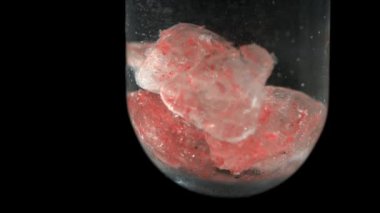 Tüpteki pembe kristaller su siyah arka planda çözünüyor, makro detayı kapat 