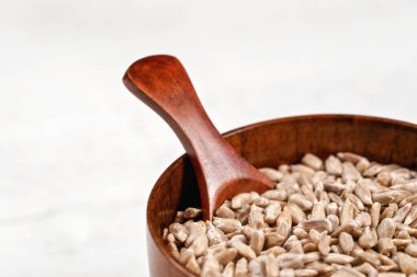 Küçük bir kepçeyle küçük tahta bardakta soyulmuş ayçekirdeği, tahta gibi beyaz bir taşın üzerine yerleştirilmiş, yakın plan detayı.