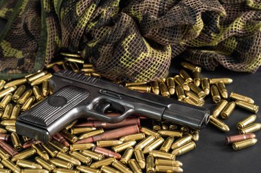 Sarı pirinç ve kahverengi bronz mermiler, yanında siyah silah, yakın plan detay.