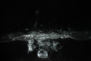 Su sıçrıyor, baloncuklar oluşuyor akvaryum tankına dökülüyor, siyah zemin.