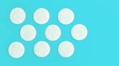 Dokuz beyaz pamuk kozmetik pedi mavi tahta üzerine dizilmiş, yukarıdan yakın çekim görüntüsü