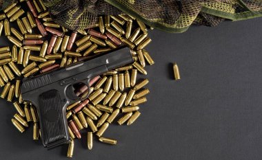 Sarı pirinç ve kahverengi bronz mermiler, yanında siyah silah, yukarıdan yakın çekim detayı, sağ tarafta metin için boşluk