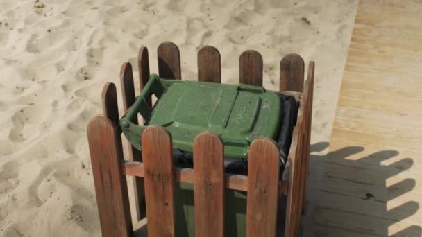 砂のビーチで緑のプラスチックごみのビンにごみを投げ 詳細を閉じます 環境を整頓する概念 — ストック動画