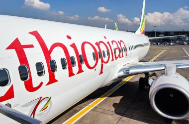 Addis Ababa, Etiyopya - 23 Nisan 2019: Etiyopya havayolları Boeing 737 güneşli bir günde arka planda Bole Uluslararası havaalanı binasında bekliyor. EAL Afrika 'nın en büyük havayolu şirketi.