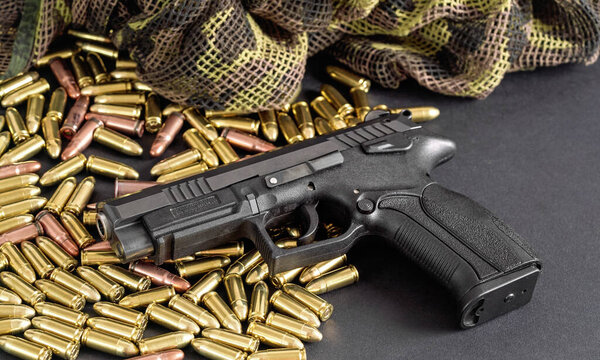 Yellow brass and brown bronze bullets, with black gun near, closeup detail