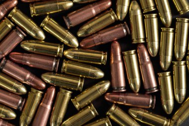 Sarı pirinç ve kahverengi bronz mermiler siyah masanın üzerinde, yukarıdan yakın plan detaylar.