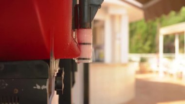 İçinde dönen buzlu çilek suyu makinesi. Biri gelip şeffaf plastik bardağa dolduruyor.