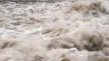 Hızlı kirli nehir dalgaları, havada uçan su damlaları, yakın çekim ayrıntıları.