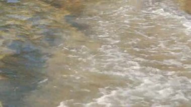 Altın renkli kumsal, güneşle aydınlatılmış, deniz suyu kıyıya vuruyor, yakın plan detayları- tropikal tatil arka planının soyut sığ derinliği