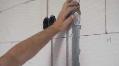 Elektrik kablosu için plastik boruyu yerleştiren inşaat işçisi çıplak duvarın içindeki kanalları kovalıyor.