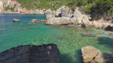 Kayalık sahil kıyısındaki oldukça sakin yeşil deniz, güneş küçük dalgalara parlıyor, Yunanistan 'ın Liapades kentindeki pek çok koydan birinde tipik manzara