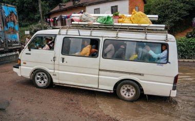 Manjakandriana, Madagaskar - 25 Nisan 2019: Yolcularla dolu küçük yerel beyaz toplu taşıma otobüsü, çatıda bagaj halatı, çamurlu kır yolu üzerinde yolculuk