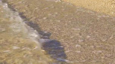 Kumsal, güneşle aydınlanıyor, deniz suyu kıyıya vuruyor, yakın plan ayrıntıları - tropikal tatil arka planının sığ derinliği