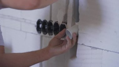 Elektrik kablosu için plastik boruyu yerleştiren inşaat işçisi çıplak duvarın içindeki kanalları kovalıyor.