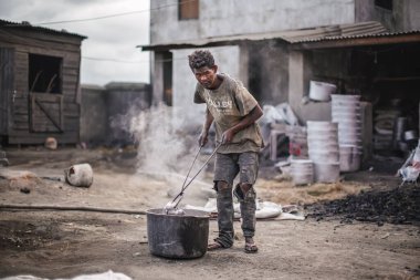 Ambatolampy, Madagaskar - 25 Nisan 2019: Alüminyum işleme fabrikası, tencereler dışarıda ateşin üzerinde eriyor, buhar yukarıda, bilinmeyen işçi elinde uzun maşayla metal parçası tutuyor.