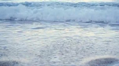 Kıyıdaki küçük deniz dalgaları kumlu plajları silip süpürüyor.