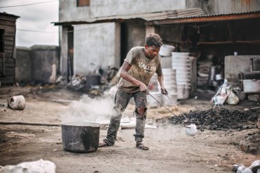Ambatolampy, Madagaskar - 25 Nisan 2019: Alüminyum işleme fabrikası, tencereler dışarıda ateşin üzerinde eriyor, buhar yukarıda, bilinmeyen işçi elinde uzun maşayla metal parçası tutuyor.
