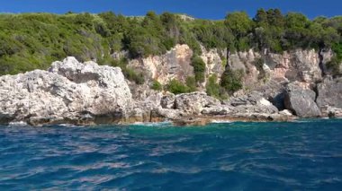 Keskin yüksek kayalık kayalıklar ve açık yeşil suyun üzerinde görünen kozalaklı ağaçlar - Liapades, Korfu Yunanistan yakınlarındaki tipik deniz manzarası, bir tekneden görülüyor