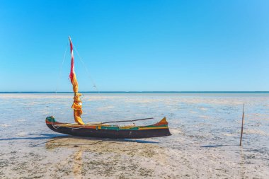 Balıkçı pirogası (yelkenli küçük balıkçı teknesi) güneşli bir günde alçak deniz kıyısında bekliyor