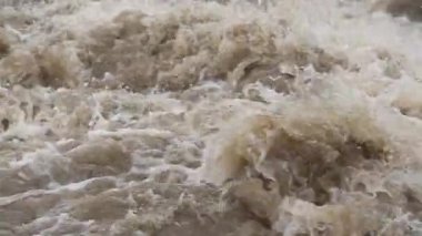 Rapid dirty river waves, drops of water flying in air, closeup slow motion video