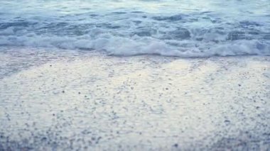 Kıyıdaki küçük deniz dalgaları kumlu plajları silip süpürüyor.