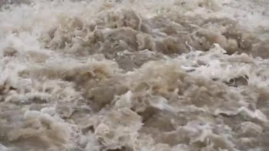 Rapid dirty river waves, drops of water flying in air, closeup slow motion video