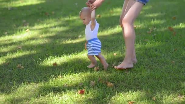 Niño feliz dando los primeros pasos en un parque — Vídeo de stock